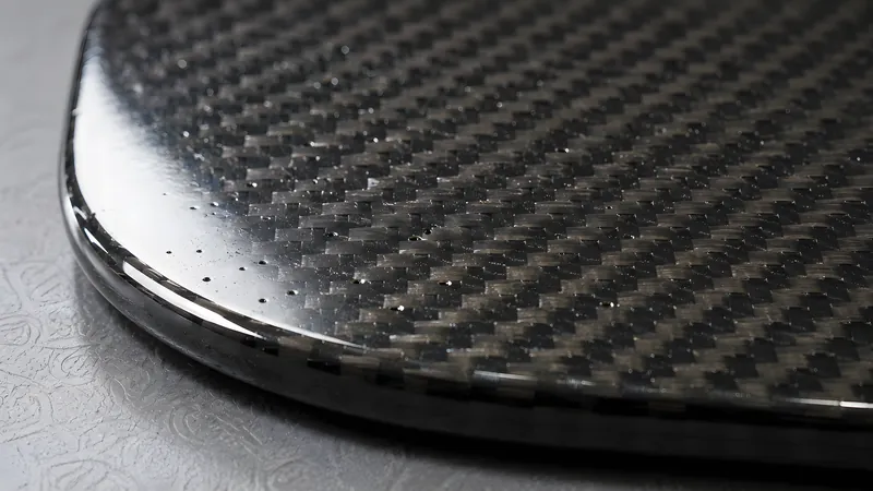 Winzige Pinholes in der glänzenden Carbon-Oberfläche im Streiflicht
